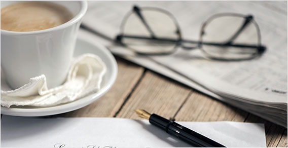 A cup of coffee and a pen on a table