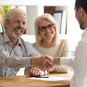 Two persons shaking hands in front of women