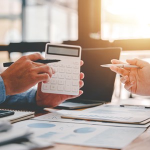 Group of professionals analyzing data on a spreadsheet with a calculator